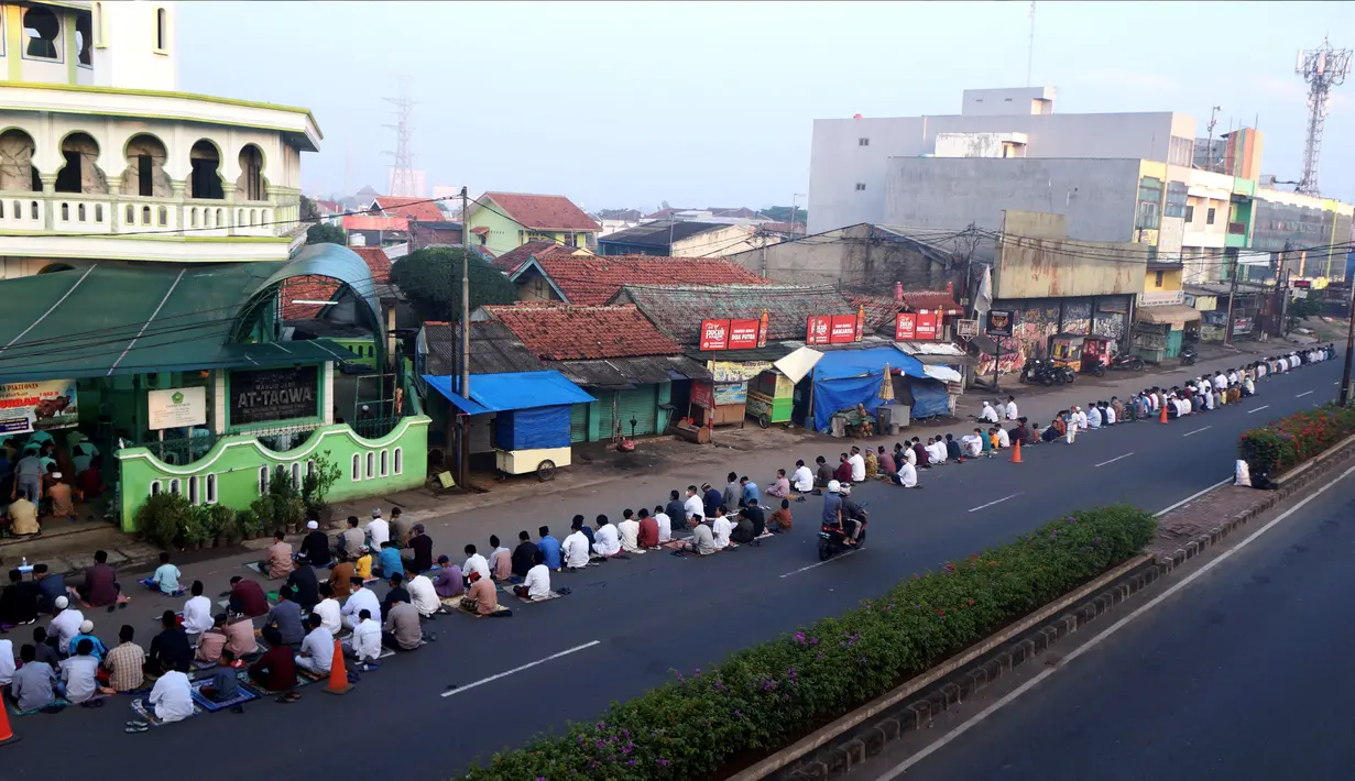 Umat muslim menerapkan jaga jarak saat melaksanakan salat Idul Adha di luar sebuah masjid di Tangerang Selatan, Banten, Selasa (20/7/2021). Umat muslim Indonesia melewati Hari Raya Idul Adha tahun ini di tengah gelombang virus corona COVID-19. (FAJRIN RAHARJO/AFP)
