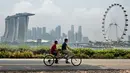 Dua orang bersepeda sambil mengamati skyline kota Singapura yang diselimuti kabut. Meskipun Singapura adalah kota dengan biaya hidup paling tinggi di dunia, namun biaya hidup di sana 10% lebih murah dibandingkan di New York. (AFP PHOTO/Roslan RAHMAN)
