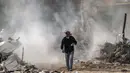 Seorang pria Palestina berjalan dengan secangkir kopi melewati debu dari pembongkaran sebuah bangunan yang hancur selama konflik Mei 2021 antara Hamas dan Israel di Kota Gaza, Sabtu (5/6/2021). (MAHMUD HAMS/AFP)