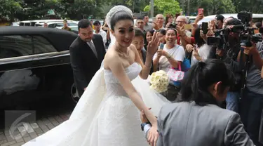 Aktris Sandra Dewi melambaikan tangan sambil berjalan masuk ke Gereja Katedral, Jakarta Pusat, Selasa (8/11). Hari ini, Sandra Dewi akan mengucap janji suci pernikahan dengan sang kekasih, Harvey Moeis . (Liputan6.com/Herman Zakharia)