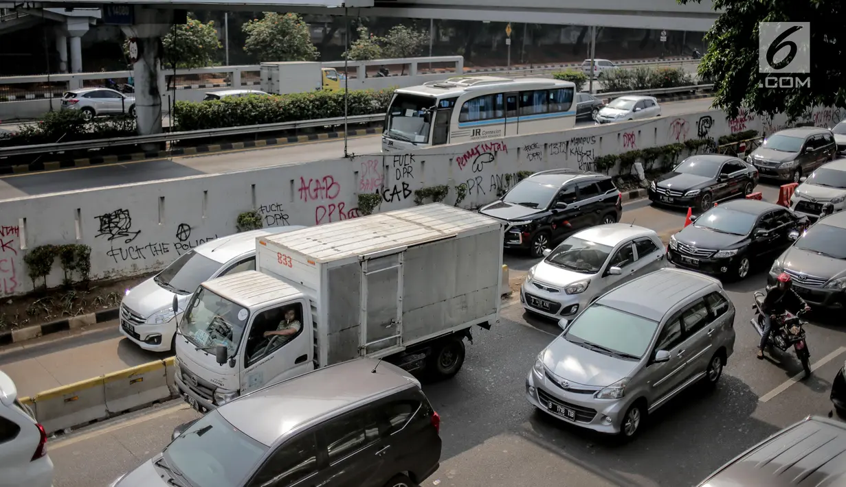 Pengendara melintasi dekat coret-coretan (vandalisme) di sekitar Gedung DPR/MPR RI, Jakarta, Selasa (24/9/2019). Demonstrasi mahasiswa dari berbagai kampus yang menolak pengesahan RUU Kitab Undang-Undang Hukum Pidana(KUHP) tercoreng oleh aksi vandalisme. (Liputan6.com/Faizal Fanani)