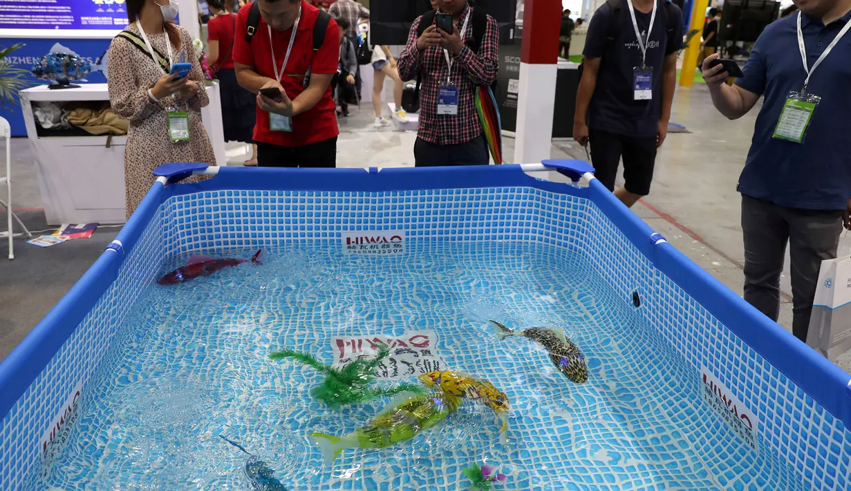 Pengunjung melihat ikan robot buatan Hiwao saat China International Robot Show di Shanghai (10/7/2019). Pameran yang menghadirkan robot-robot canggih ini diselenggarakan dari 10 sampai 13 Juli 2019. (AFP Photo/STR)