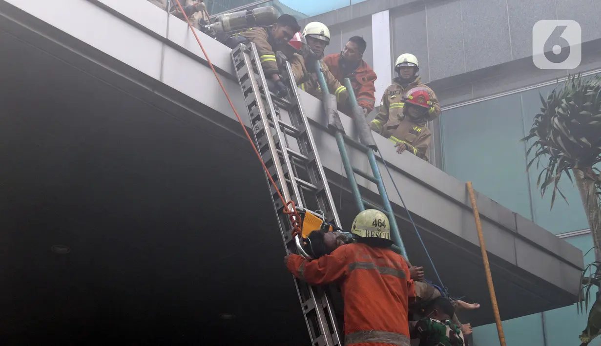 Petugas pemadam kebakaran mengevakuasi korban kebakaran di Gedung Cyber 1, Jakarta, Kamis (2/12/2021). Petugas pemadam kebakaran membutuhkan waktu kurang lebih 30 menit untuk mengevakuasi para korban. (Liputan6.com/Herman Zakharia)