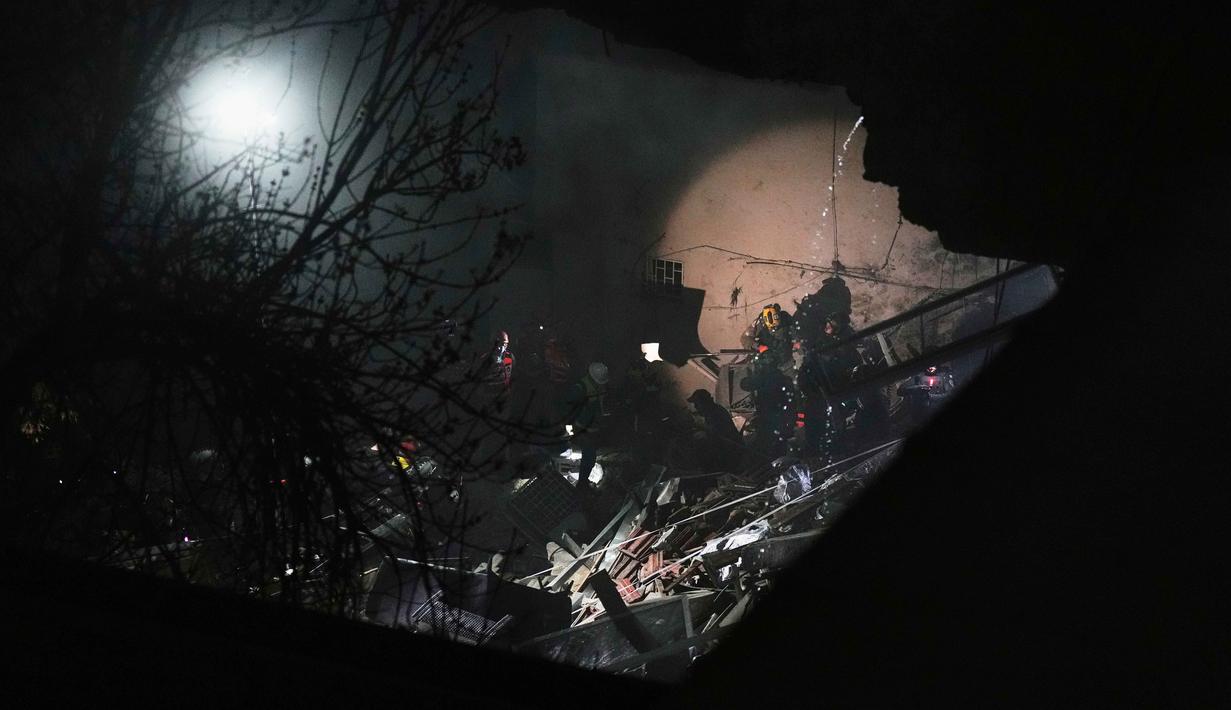 Kekuatan serangan rudal Iran tersebut menyebabkan sebagian pondasi bangunan dan lantai bawahnya runtuh. Tampak dalam foto, pasukan keamanan Israel dan tim penyelamat melakukan upaya pencarian korban di tengah reruntuhan bangunan tempat tinggal yang dihantam rudal Iran di Haifa, Israel, Minggu, 5 April 2026. (AP Photo/Ariel Schalit)