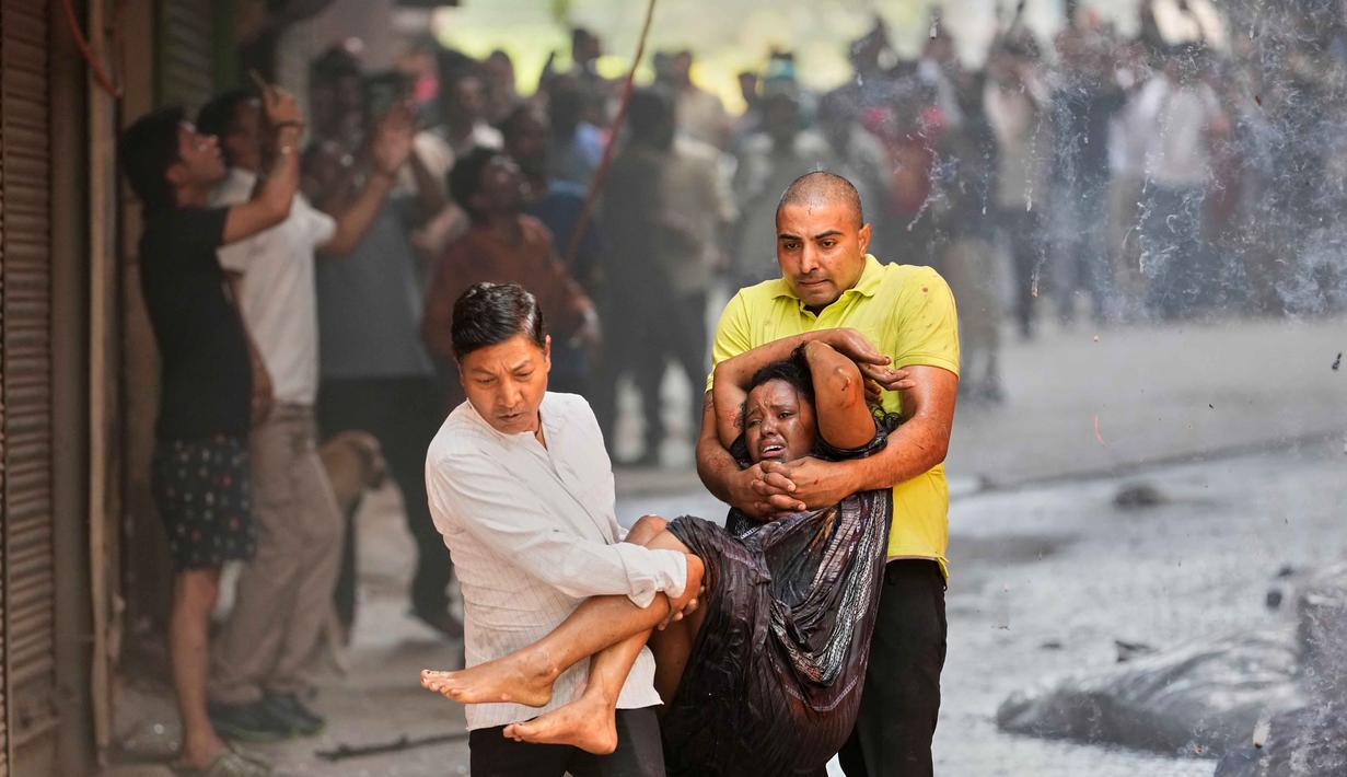 Salah satu keluarga warga negara asing tergantung di jendela hotel saat api melalap bangunan sebuah hotel di New Delhi, India, Rabu 3 Juni 2026. (AP Photo/Manish Swarup)