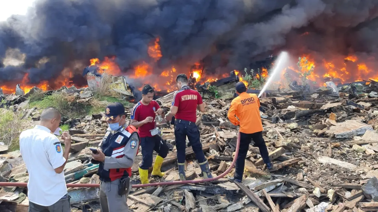 Petugas BPBD Situbondo berjibaku  memadamkan api  yang membakar tumpukan kapal beas di Pelambuhan Baru Situbondo (Istimewa)