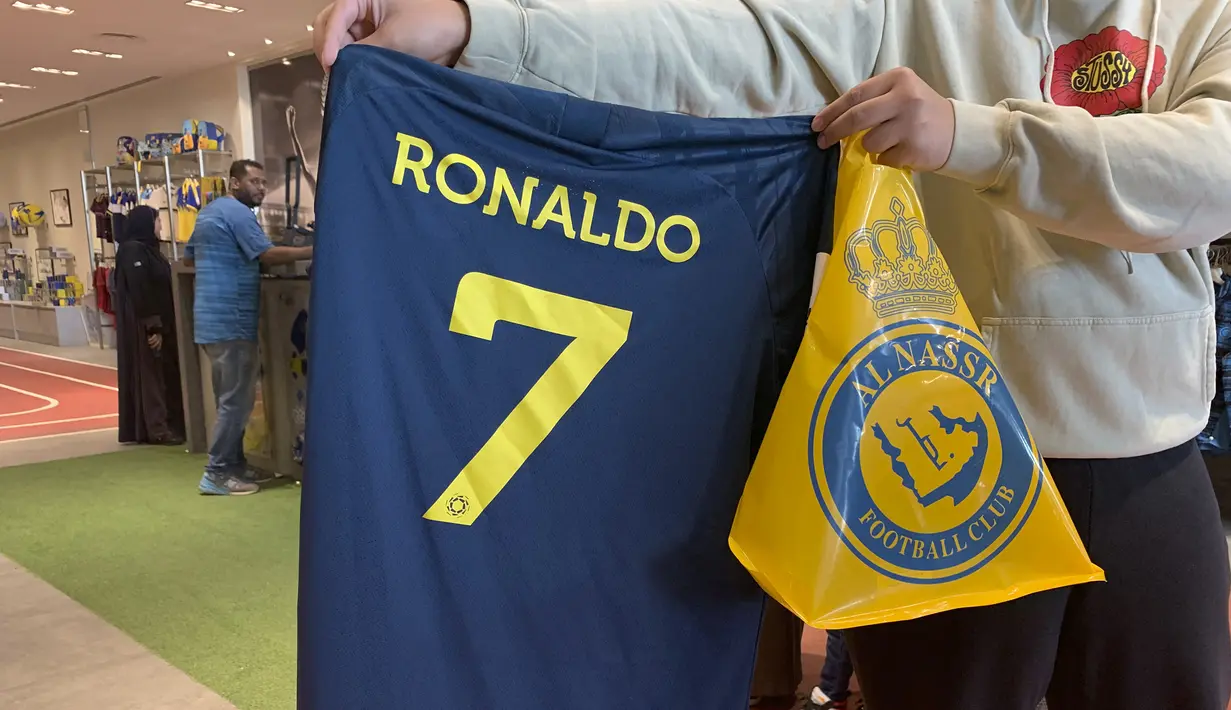 Kepastian bergabungnya Cristiano Ronaldo pada 31 Desember 2022 bersama klub papan atas Arab Saudi, Al Nassr langsung berpengaruh signifikan dari sisi bisnis. Para fans Al Aalami, julukan bagi Al Nassr, berbondong-bondong mengunjungi toko resmi pernak-pernik klub Al Nassr di Riyadh untuk berburu jersey bernomor punggung 7 bertuliskan "Ronaldo". (AFP/Fayez Nureldine)