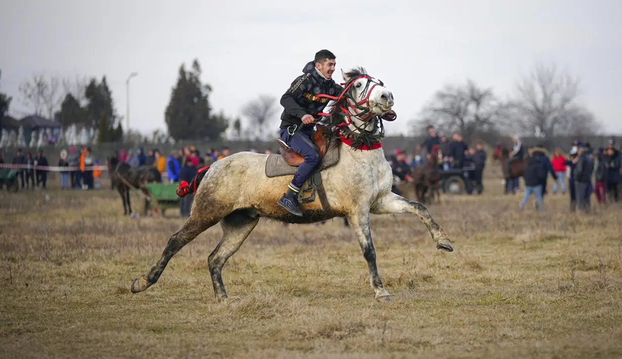 Seorang pria menunggang kuda saat perayaan Epiphany di Desa Pietrosani, Rumania, 6 Januari 2022. Epiphany adalah sebuah hari raya keagamaan dalam sejumlah denominasi gereja Kristen pada tanggal 6 Januari. (AP Photo/Vadim Ghirda)