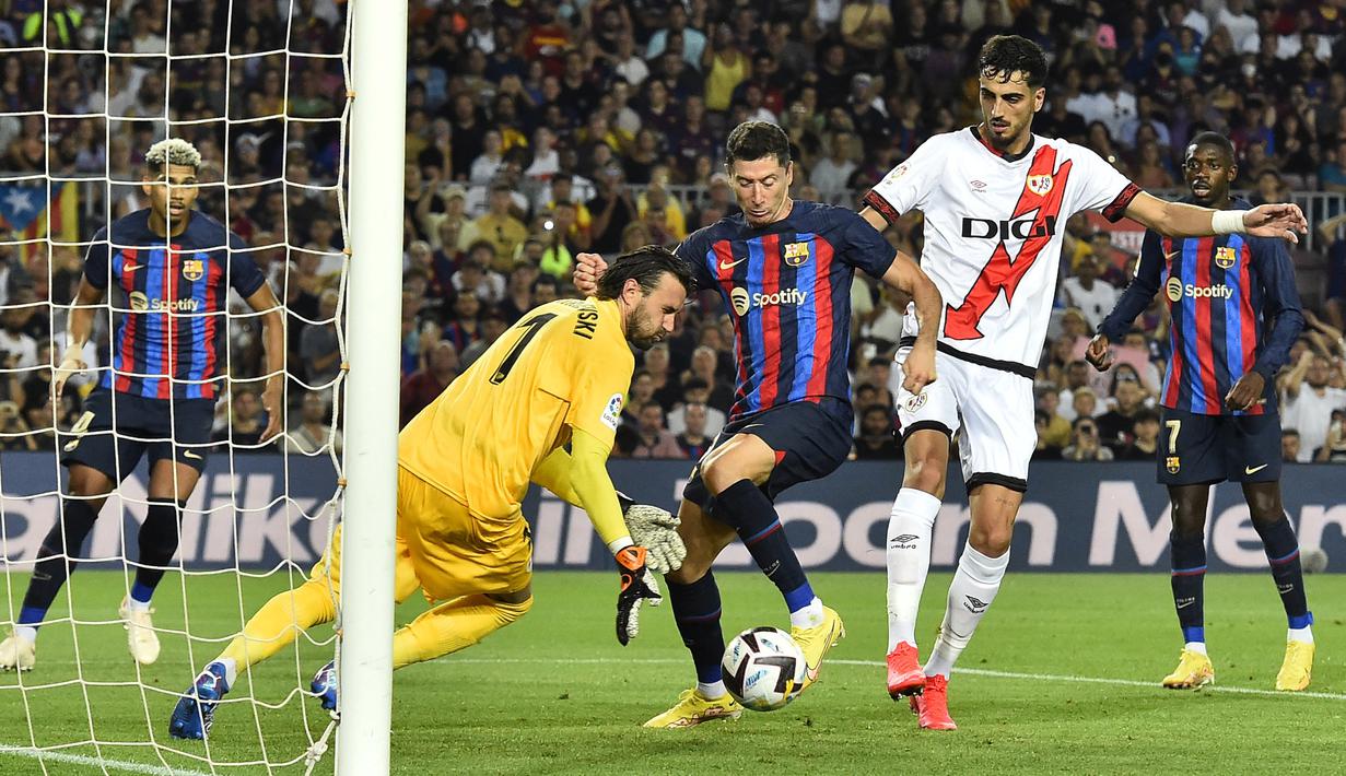 Pemain Barcelona, Robert Lewandowski mengontrol bola dan berusaha menjebol gawang Rayo Vallecano yang dijaga oleh Stole Dimitrievski. Lewandowski yang merupakan pemain anyar Barcelona bermain 90 menit dan beberapa kali mengancam gawang lawan. Namun tidak satupun gol yang ia ciptakan. (AFP/Pau Barrena)