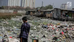 Seorang anak terlihat di dekat permukiman kumuh yang berdiri di atas tumpukan sampah di Kampung Bengek, Jakarta Utara, Selasa (3/9/2019). Permukiman kumuh ini berdiri di atas rawa yang membeku karena timbunan sampah plastik, kasur bekas hingga limbah rumah tangga. (Liputan6.com/Faizal Fanani)