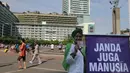 Seorang aktivis membentangkan spanduk tertulis 'janda juga manusia' saat melakukan aksi peringatan Hari Ibu di Bundaran HI, Jakarta, Minggu (21/12/2014). (Liputan6.com/Herman Zakharia)