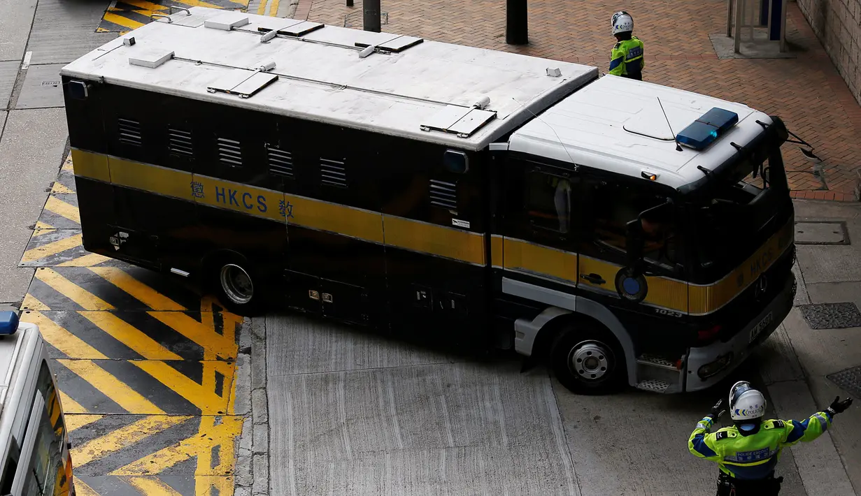 Seorang polisi mengarahkan mobil penjara yang membawa Rurik Jutting ke Pengadilan Tinggi di Hong Kong, Selasa (25/10). Jutting didakwa atas pembunuhan WNI di Hong Kong, SM dari Jawa Tengah dan JL dari Sulawesi pada tahun 2014. (Reuters/Bobby Yip)