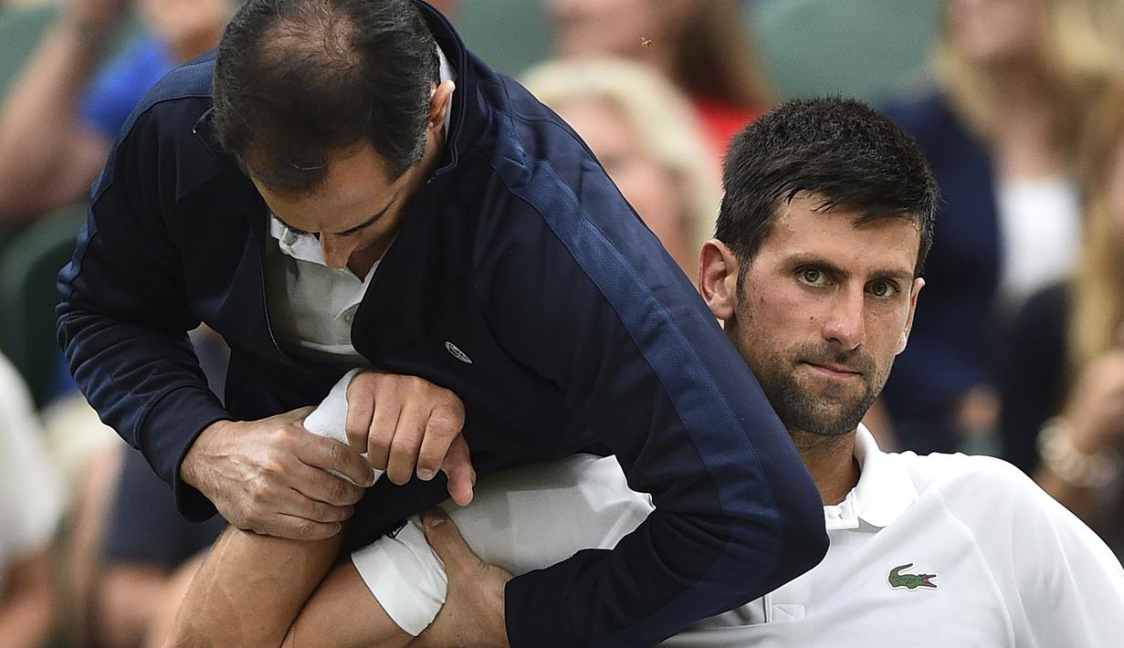Ekspresi Novak Djokovic ketika mendapat perawatan medis pada lengan kanan saat melawan Adrian Mannarino pada Wimbledon 2017 di The All England Lawn Tennis Club, London, (11/7/2017). (AFP/Glyn Kirk)