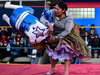 Pegulat Bolivia, Ana Luisa Yujra (kanan) membanting lawannya pegulat pria di atas ring gulat di El Alto, pada 24 November 2019. Di Bolivia ada sebuah atraksi gulat yang diperankan perempuan dengan menggunakan busana khas warga Bolivia. (Ronaldo SCHEMIDT / AFP)