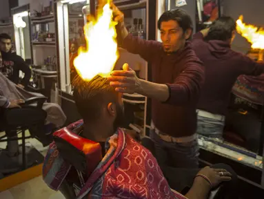 Ramadan Edwan, seorang tukang cukur asal Palestina, menggunakan api untuk mencukur rambut pelanggannya di sebuah barbershop di kamp pengungsian Rafah, di selatan Jalur Gaza, Rabu (1/2). (MAHMUD HAMS/AFP)