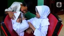 Kembar siam Al Dewi Putri Ningsih (9) dan Al Putri Anugrah (9) saat bercengkerama dengan sang kakak di rumah mereka kawasan Sucinaraja, Garut, Jawa Barat, Senin (22/5/2023). (merdeka.com/Arie Basuki)