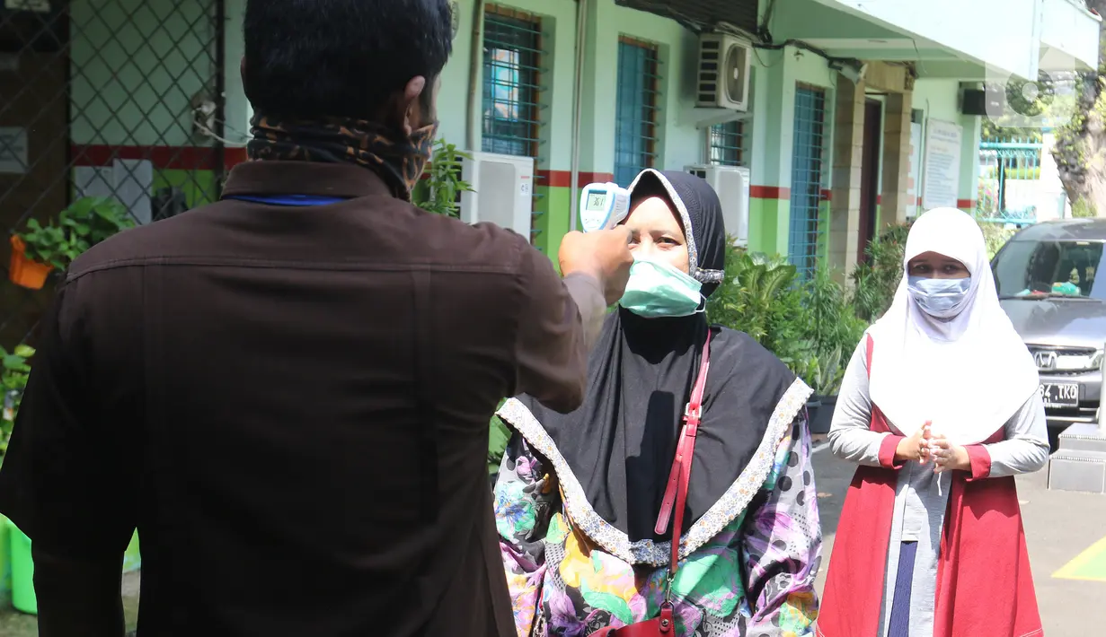 Petugas SMPN 60 Jakarta memeriksa suhu tubuh orangtua calon siswa yang akan lapor diri saat pengurusan Penerimaan Peserta Didik Baru (PPDB) di SMPN 60 Jakarta, Rabu (17/6/2020). Sejumlah sekolah di DKI Jakarta, salah satunya SMPN 60 Jakarta, membuka penerimaan peserta didik baru sejak 15 Juni 2020.