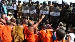 Sejumlah biksu melakukan aksi protes dengan di jaga ketat oleh petugas keamanan di kota pelabuhan selatan Hambantota, Sri Lanka (7/1). (AFP/Ishara S. Kodikara)