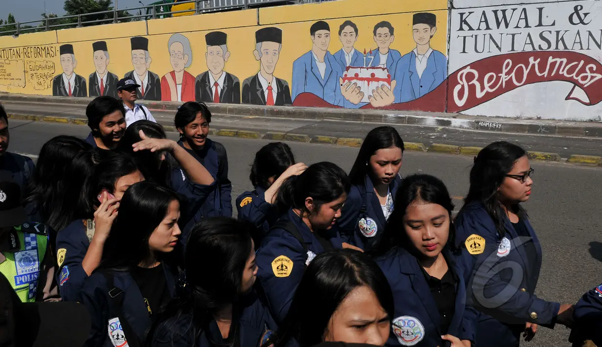 Sejumlah mahasiswa melintas di depan Mural bergambar empat mahasiswa Trisakti yang tewas pada 12 Mei 1998 lalu, Jakarta, Selasa (12/5/2015). Hingga kini pelaku dan dalang peristiwa 12 Mei 1998 belum terungkap. (Liputan6.com/Johan Tallo)