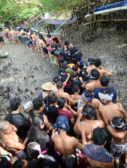Warga berjalan menyusuri hutan mangrove saat mengikuti tradisi mandi lumpur atau mebuug-buugan di Desa Kedonganan, Denpasar, Bali, Jumat (8/3). Tradisi ini bertujuan menetralkan sifat buruk. (Sonny Tumbelaka/AFP)