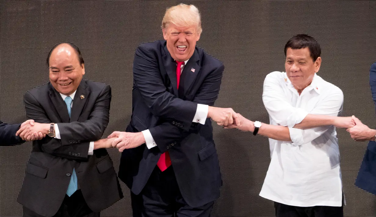 Ekspresi Presiden AS, Donald Trump saat bersalaman khas ASEAN dengan para pemimpin lainnya di penghujung upacara pembukaan KTT ASEAN di Manila, Filipina, Senin (13/11). Trump kesulitan menempatkan tangannya di posisi yang pas. (AP/Andrew Harnik)