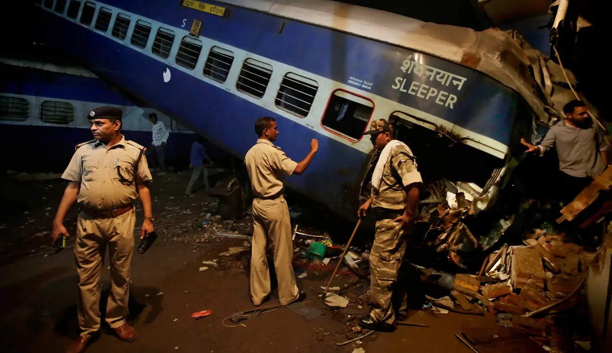 Aparat kepolisian India berdiri dekat gerbong kereta Kalinga-Utkal Express yang tergelincir hingga keluar jalur di Negara Bagian Uttar Pradesh, Minggu (20/8). Hingga kini penyebab pasti terjadinya kecelakaan tersebut masih belum diketahui (AP/Altaf Qadri)