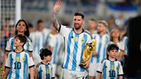 Lionel Messi berjalan ditemani Antonela Roccuzzo dan anak-anak mereka dengan membawa trofi Piala Dunia sambil menyapa para penonton. (AP Photo/Natacha Pisarenko)
