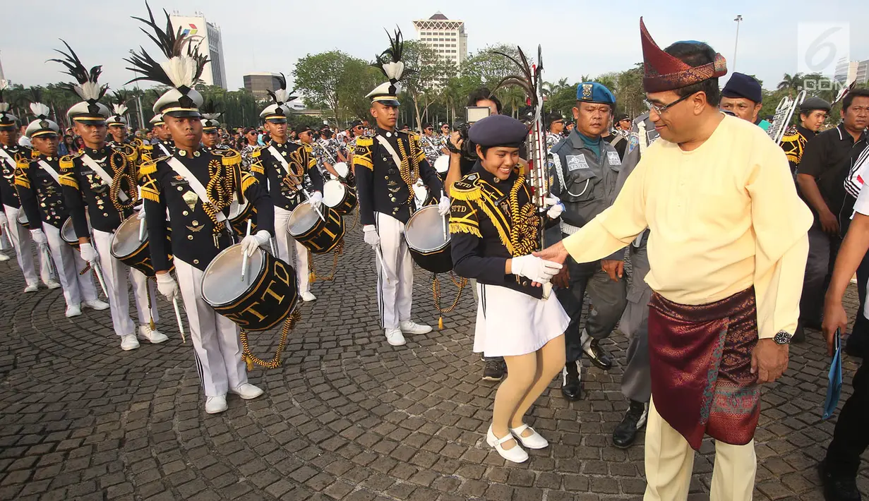 Menhub Budi Karya Sumadi menyapa salah satu pemain marching band pada acara puncak Hari Perhubungan Nasional di Lapangan Silang Monas, Jakarta, Minggu (17/9). Menhub Budi menggunakan baju khas daerahnya Palembang. (Liputan6.com/Immanuel Antonius)