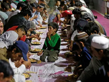 Seorang anak duduk diantara umat muslim yang sedang menikmati menu berbuka puasa di sebuah masjid di Kabul, Afganistan, 16 Juni 2016. Tradisi berbuka puasa bersama selama Ramadan merupakan momentum untuk mempererat tali persaudaraan (REUTERS/Omar Sobhani)