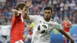 Gelandang Mesir, Trezeguet, berebut bola dengan bek Rusia, Mario Fernandes, pada laga Grup A Piala Dunia di Stadion Krestovsky, St Petersburg, Selasa (19/6/2018). Rusia menang 3-1 atas Mesir. (AP/Gregorio Borgia)