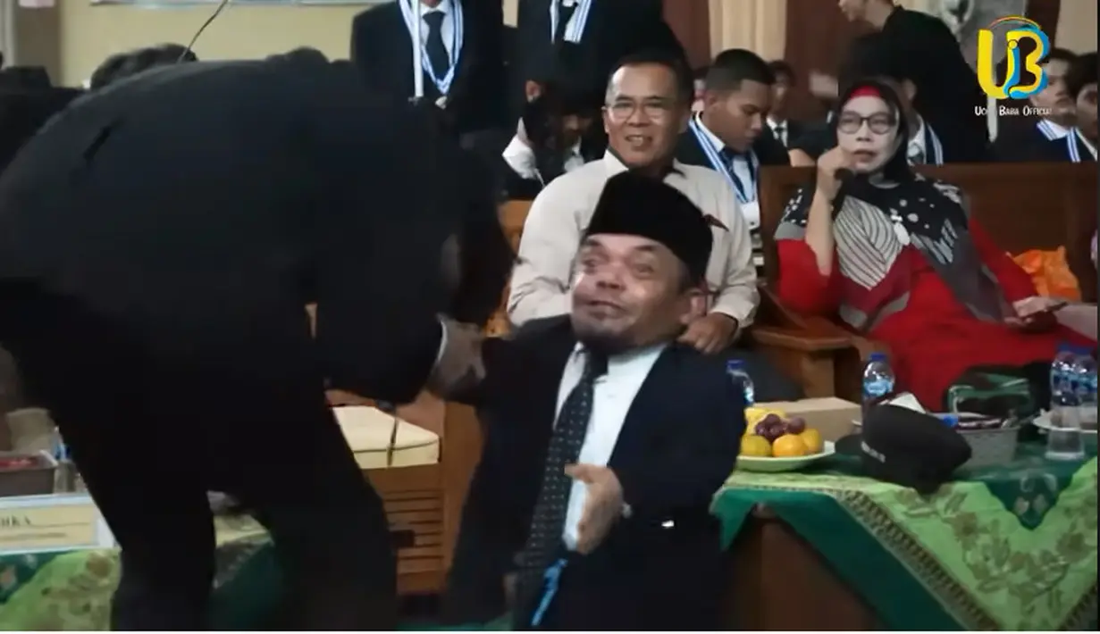 Ucok Baba menyambut sang putra yang menyalaminya ketika turun dari panggung. Potret bahagia dan bangga begitu terlihat karena putranya sudah lulus SMK dan siap melanjutkan untuk kuliah. [Youtube/Ucok Baba official]