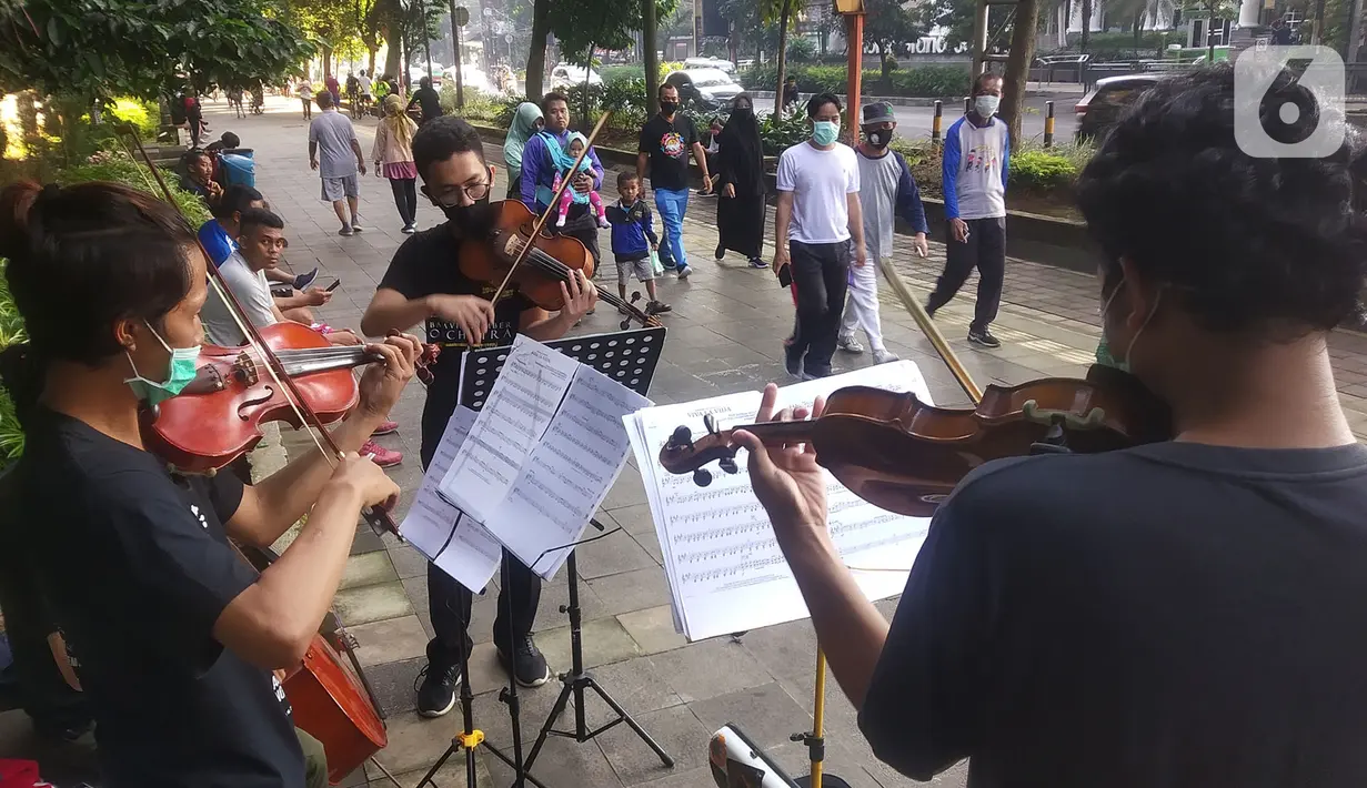 Musisi lokal Bogor memainkan musik klasik di pedestrian Kebun Raya, Jalan Pajajaran, Bogor, Jawa Barat, Minggu (14/6/2020). Untuk memenuhi kebutuhan hidup akibat sepinya job pertunjukan selama pandemi COVID-19, mereka memilih mengamen saat warga berolahraga. (merdeka.com/Arie Basuki)