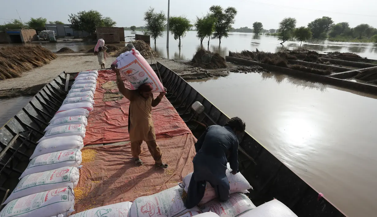Para petani memuat sekantong benih jagung ke dalam perahu saat mereka mengungsi dari daerah banjir di kota Burewala, di distrik Vehari di provinsi Punjab, pada 25 Agustus 2023. (AFP/Shahid Saeed Mirza)