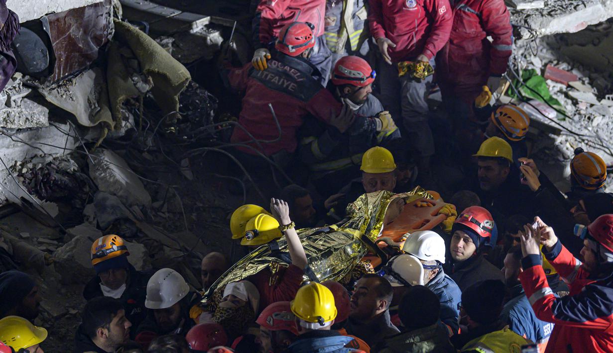Seher, seorang wanita Suriah berusia 15 tahun mengangkat tangannya saat dia dibawa dengan tandu oleh petugas penyelamat setelah diselamatkan dari bawah reruntuhan tempat dia terjebak di Hatay, tenggara Turki, pada 14 Februari 2023. Seher berhasil diselamatkan setelah terperangkap di bawah reruntuhan selama 210 jam seminggu setelah gempa mematikan melanda sebagian dari Turki dan Suriah. (AFP/Yasin AKGUL)