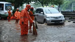 Petugas PPSU Kel Kuningan Barat melokalisir sebagian jalan di putaran kolong fly over Kapt Tendean, Jakarta, Selasa (9/2/2016). Hujan yang mengguyur Jakarta, Selasa (9/2) sore mengakibatkan putaran ini tergenang air. (Liputan6.com/Helmi Fithriansyah)