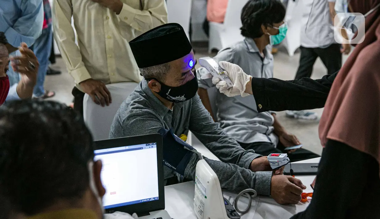Petugas kesehatan memeriksa suhu tubuh seorang pemuka agama sebelum menjalani Vaksinasi COVID-19 di Mesjid Istiqlal, Jakarta, Selasa (23/2/2021). Pemuka agama yang mengikuti vaksinasi ini mencapai ribuan orang. (Liputan6.com/Faizal Fanani)