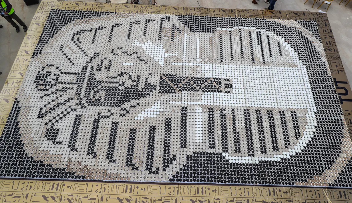 Mosaik topeng Firaun Tutankhamun yang terbuat dari cangkir kopi di halaman Museum Grand Mesir di Giza, 28 Desember 2019. Orang-orang bergabung lebih dari 12 jam mengubah warna kopi dengan memasukkan susu dengan jumlah yang berbeda. (Mohamed el-Shahed/AFP)