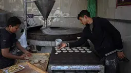 Kawasan Timur Tengah memiliki tradisi menikmati kue atau kudapan khas Ramadan, seperti Qatayef dan Kunafa. Tampak dalam foto, seorang pembuat dan pedagang roti Mesir membuat Qatayef, pancake tradisional yang dibuat selama bulan puasa suci Ramadan, di tokonya, Kairo, Mesir, pada Kamis 12 Maret 2026. (Khaled DESOUKI/AFP)