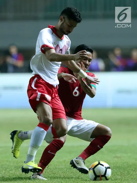 Pemain tengah Indonesia U-23, Evan Dimas Darmono (kanan) berusaha menahan pemain pergerakan Bahrain pada laga PSSI Anniversary 2018 di Stadion Pakansari, Kab Bogor, Jumat (27/4). Indonesia kalah 0-1. (Liputan6.com/Helmi Fithriansyah)