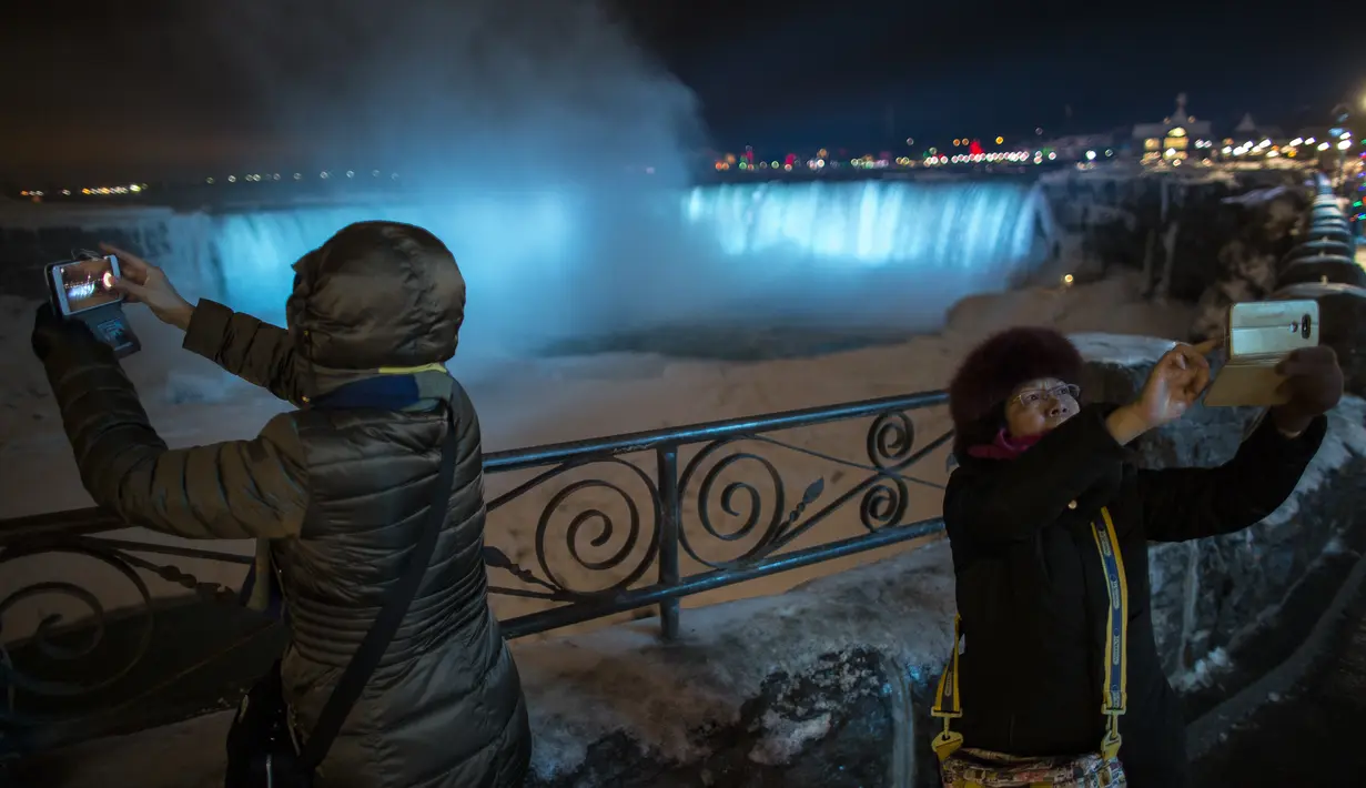 Dua oranga turis selfie di depan Air Terjun Niagara, Ontario, Kanada, Senin (9/1). Topan besar menerjang pantai timur Amerika Serikat pada 5 Januari lalu. (Geoff Robins/AFP)