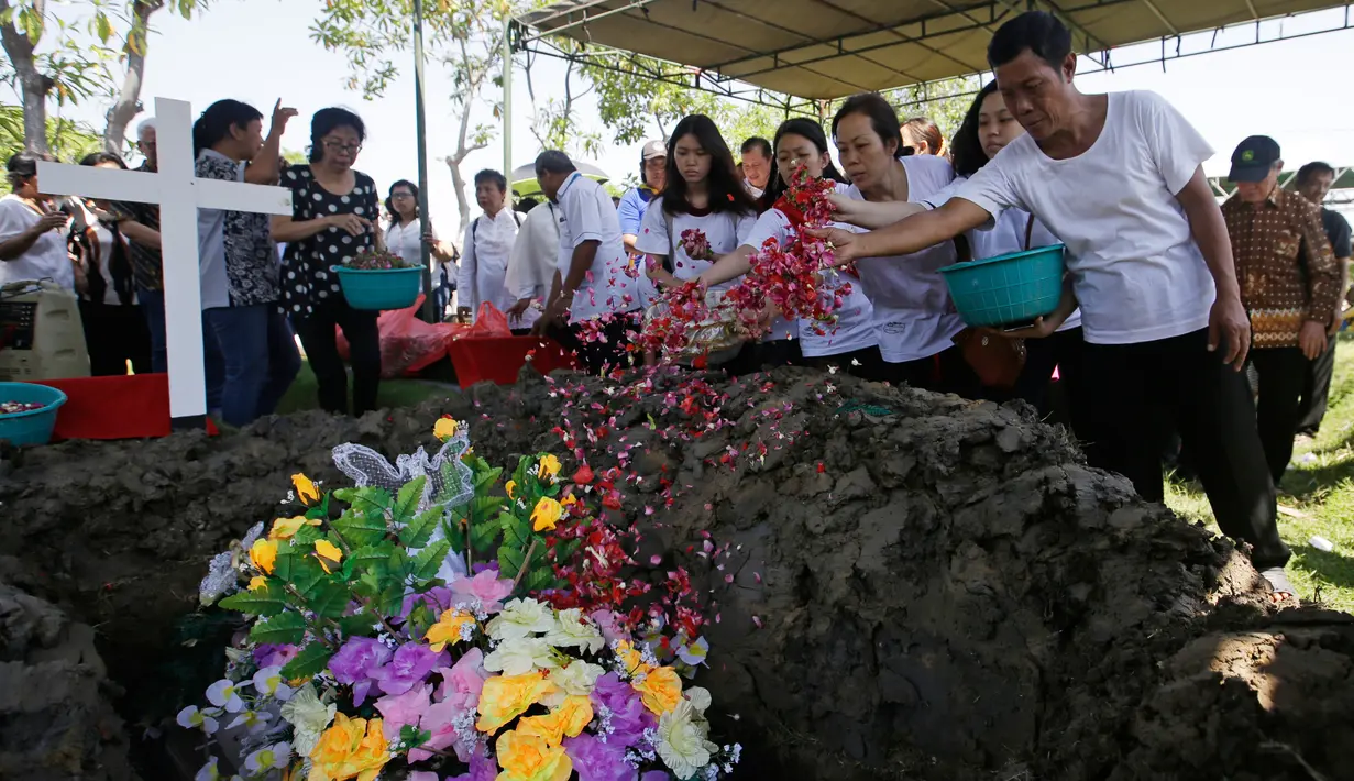 Keluarga korban bom gereja Surabaya menabur bunga pada pemakaman Martha Djumani di komplek Taman Makam Keputih, Surabaya, Rabu (16/5). Martha merupakan korban bom bunuh diri di Gereja Pantekosta Pusat Surabaya Minggu (13/5) lalu. (AP/Achmad Ibrahim)