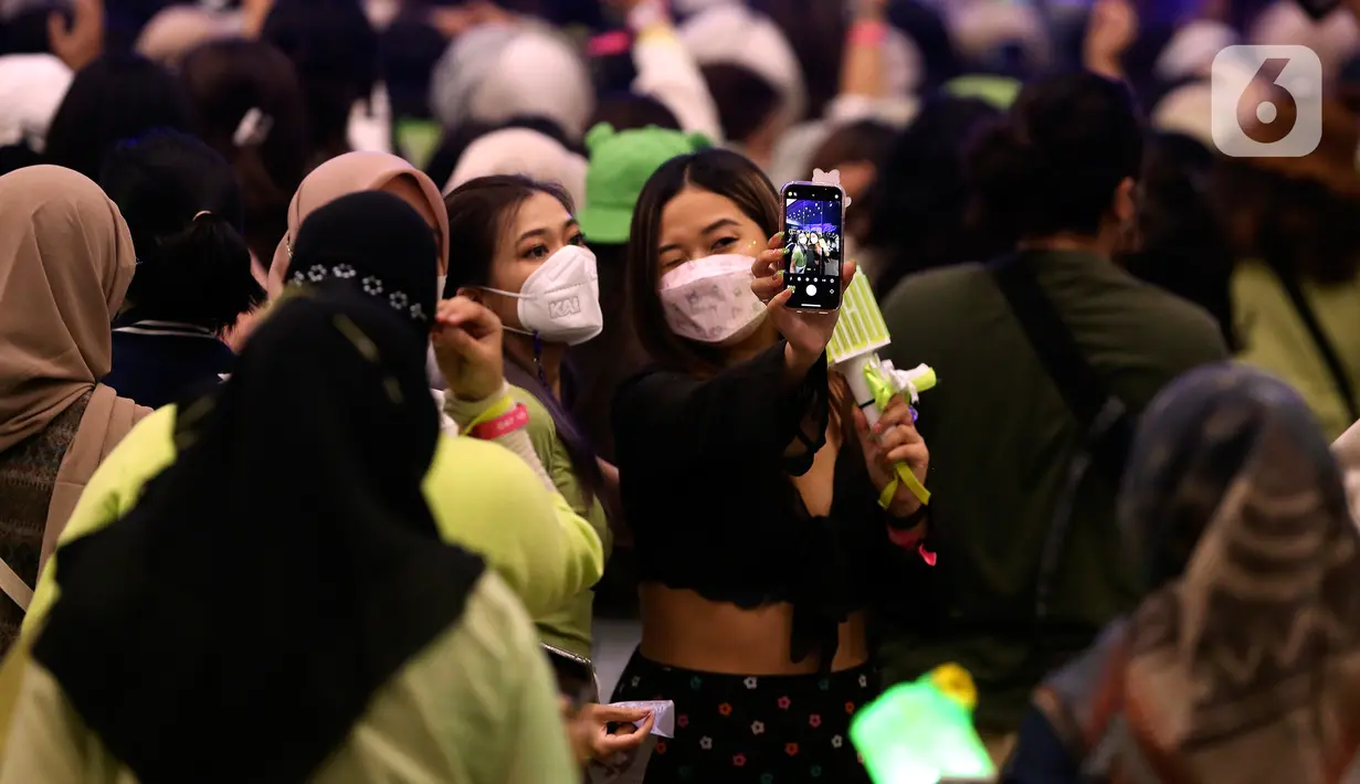 Penggemar NCT 127, NCTzen berswafoto saat menunggu grup idolanya tampil dalam tur konser dunia kedua bertajuk "NEO City: Jakarta - THE LINK" di ICE BSD City, Tangerang, Banten, Jumat (4/11/2022). Konser dimulai tepat pukul 19.00 WIB dan dibuka dengan lagu 'Indonesia Raya'. (Liputan6.com/Johan Tallo)