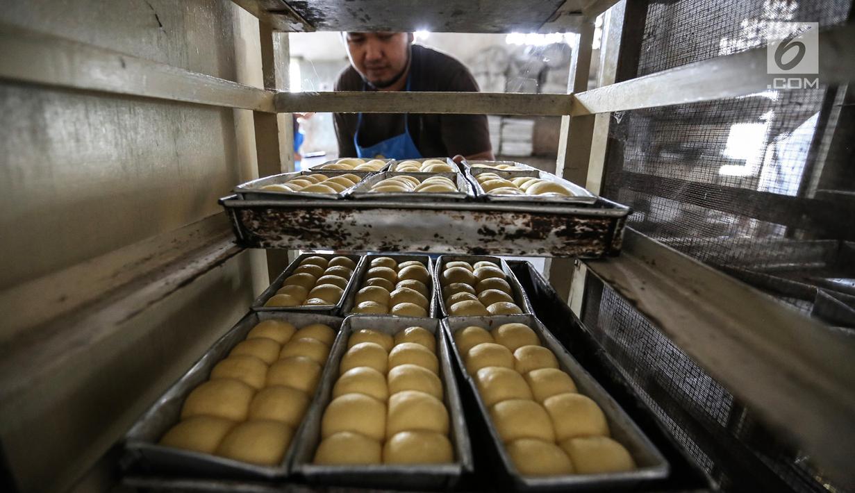 Karyawan mengambil roti yang akan di panggang ke dalam tungku di Toko Roti GO, Purwokerto, Jawa Tengah, Senin (22/4). Toko roti yang berdiri sejak tahun 1898 tersebut diproduksi dengan fermentasi (bibit roti) dan tanpa bahan campuran atau pengawet. (Liputan6.com/Fery Pradolo)