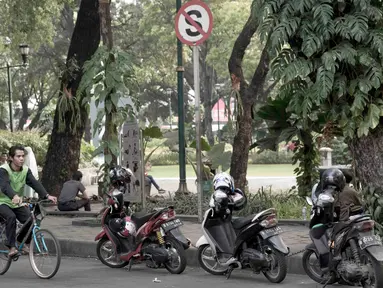 Pengendara sepeda melintas di samping deretan sepeda motor yang terparkir di sekitar Taman Suropati, Jakarta, Selasa (28/8). Meski terpampang rambu larangan parkir dan berhenti, pengendara tetap parkir di sekitar taman. (Liputan6.com/Immanuel Antonius)