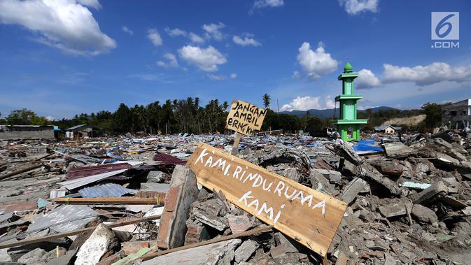 Sebuah papan dengan pesan Kami Rindu Rumah Kami dipasang pasca gempa bumi dan tsunami di pinggir Jalan Trans Sulawesi, Palu, Sulawesi Tengah, Kamis (4/10). (Liputan6.com/Fery Pradolo)