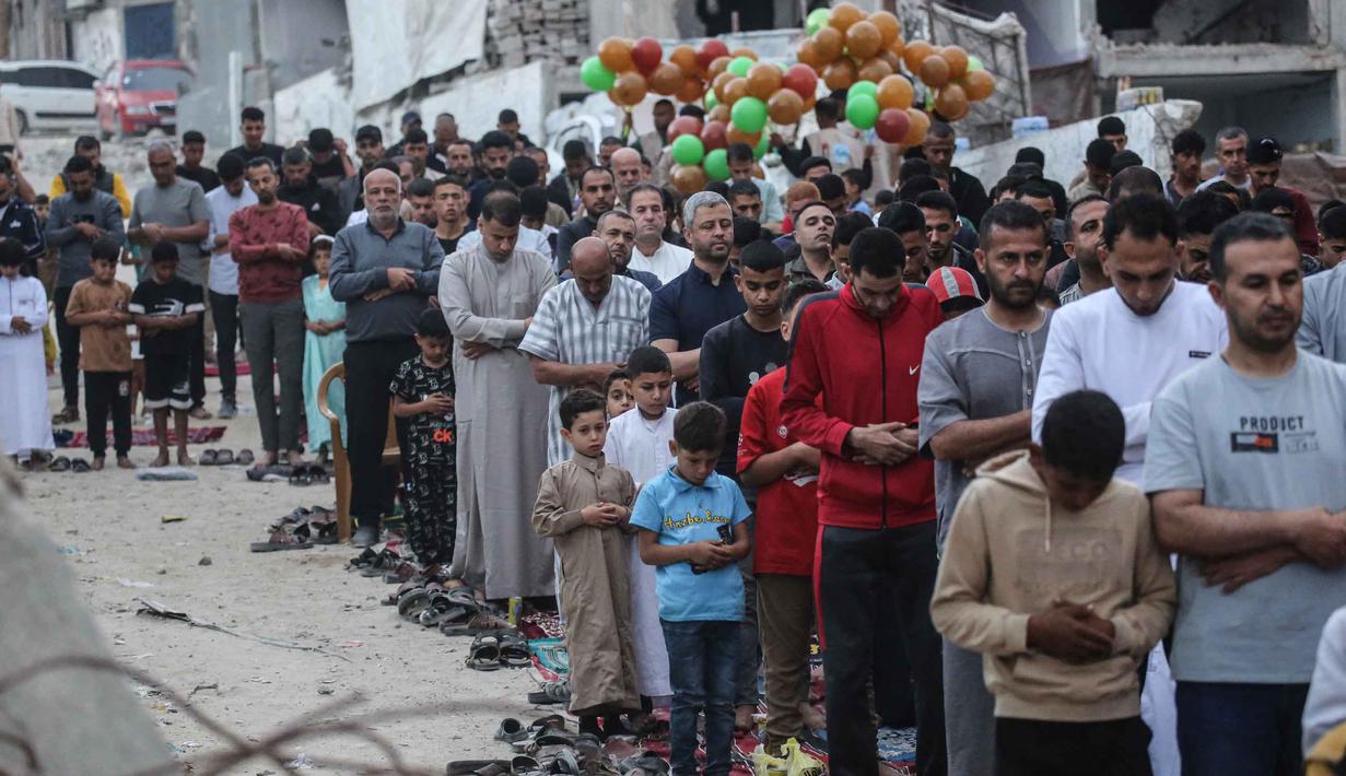 Warga Palestina melaksanakan salat menandai dimulainya Idul Adha, Hari Raya Kurban, di jalan yang rusak parah di Khan Yunis, Jalur Gaza Selatan, pada Rabu 27 Mei 2026. (BASHAR TALEB/AFP)
