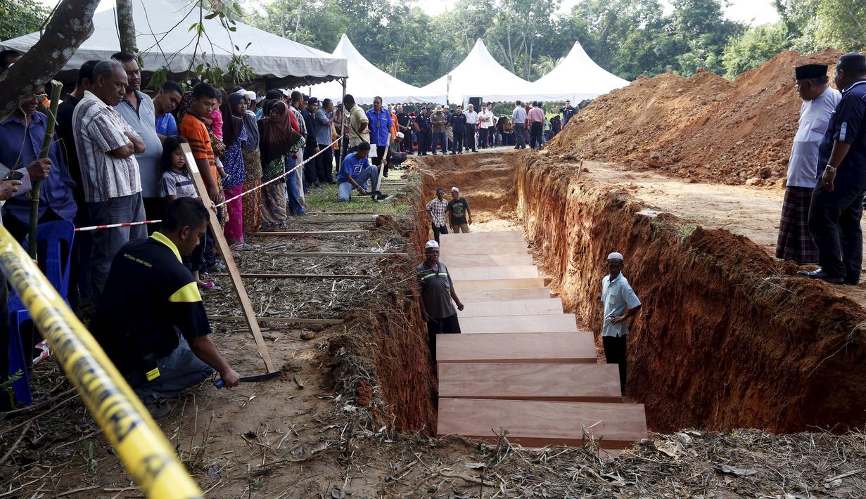Sejumlah orang menyaksikan pemakaman massal jenazah yang di duga etnis Rohingya di Alor Setar, Malaysia, Senin (22/6/2015).  21 dari 106 jenazah tak dikenal yang ditemukan bulan lalu dimakamkan hari ini. (Reuters/Olivia Harris)