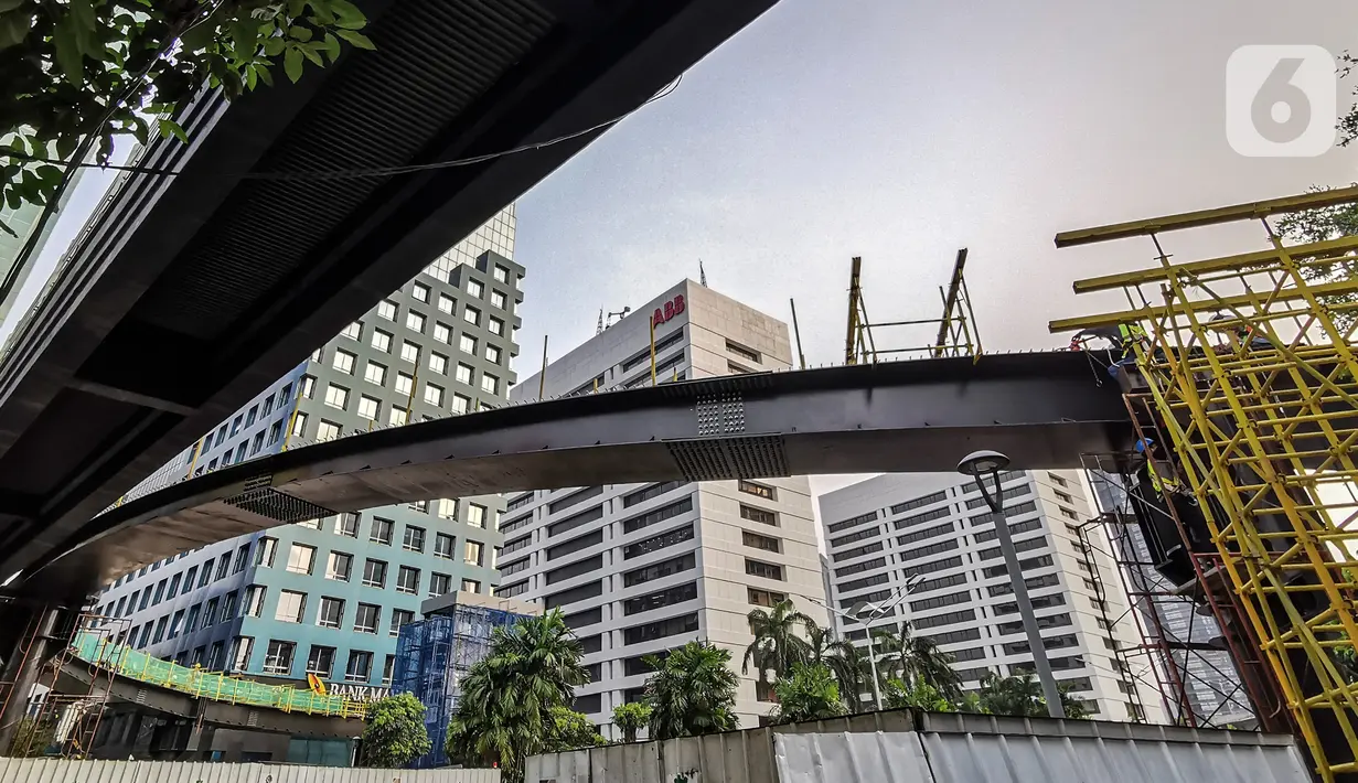 Pekerja menyelesaikan pengerjaan jembatan penyeberangan orang (JPO) dan jembatan penyeberangan sepeda di Karet Sudirman, Jakarta, Jumat (8/10/2021). Jembatan penyeberangan dengan konsep modern yang dilengkapi anjungan bertema kapal pinisi ini sudah mencapai 70 persen. (Liputan6.com/Johan Tallo)