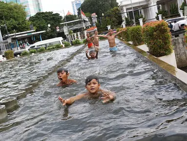 Anak-anak berenang di kolam air mancur penghias kawasan Pasar Baru, Jakarta, Selasa (29/1). Keterbatasan lahan bermain menyebabkan sebagian anak di Ibukota bermain tidak pada tempatnya, meskipun berbahaya bagi keselematan. (Liputan6.com/Immanuel Antonius)
