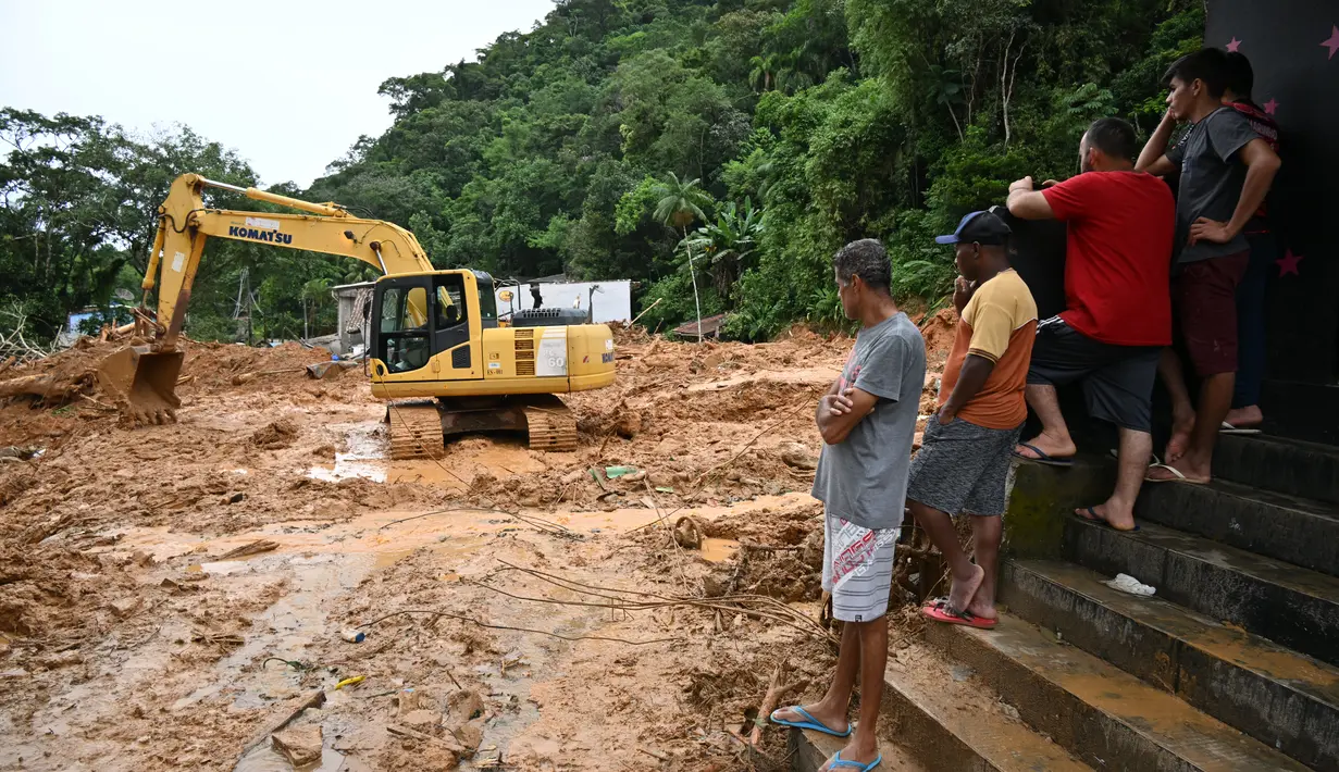 Sebuah buldoser membersihkan lumpur di daerah yang terkena banjir di distrik Juquehy di Sao Sebastiao, negara bagian Sao Paulo, Brasil (20/2/2023). Dampak bencana itu membuat perayaan karnaval di kota-kota tersebut terpaksa dibatalkan, dengan tim penyelamat berjuang untuk mencari korban hilang, korban luka dan dikhawatirkan tewas tertimbun puing-puing. (AFP/Nelson Almeida)